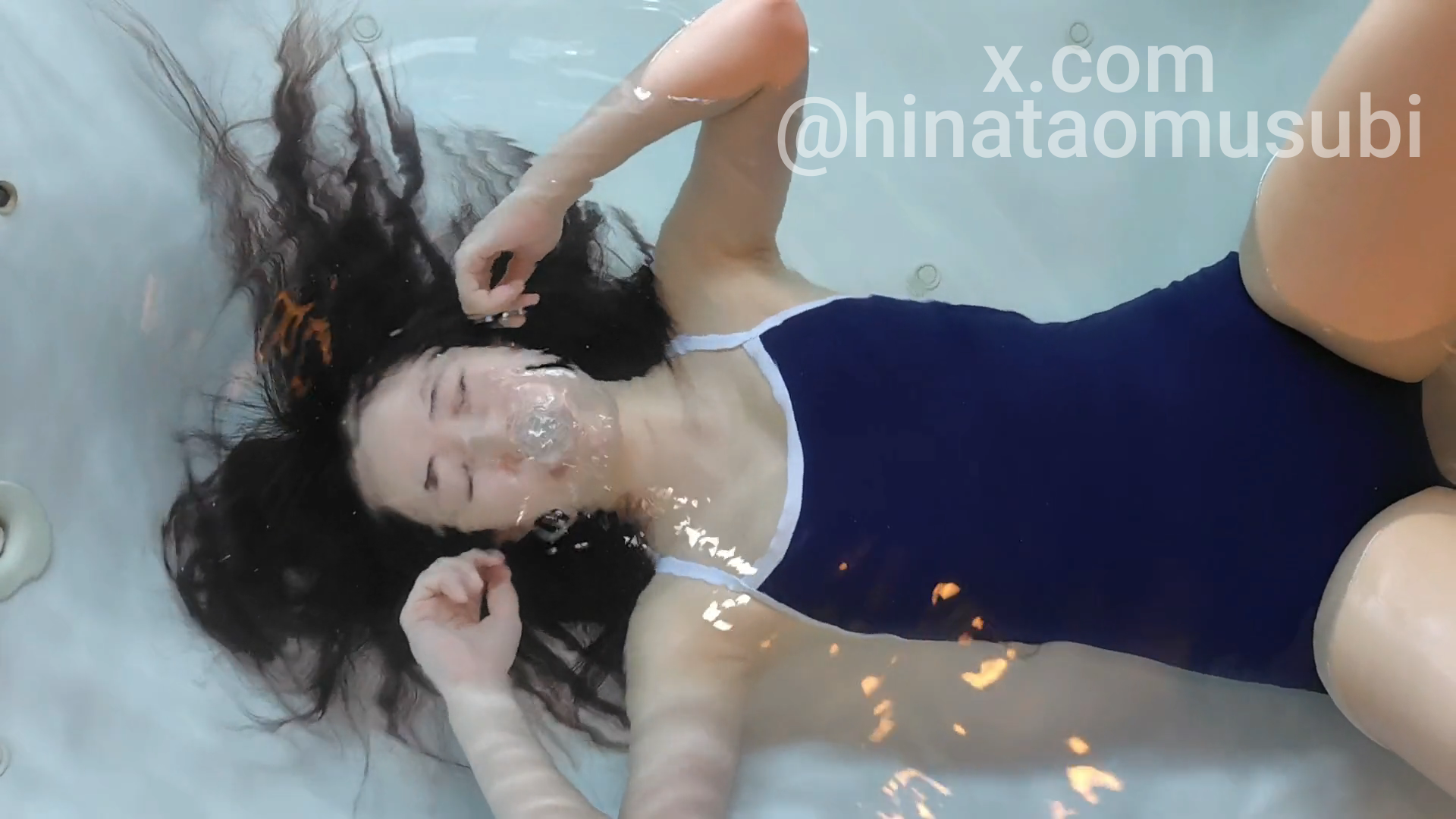 水中で苦悶し鼻から気泡が漏れる女の競泳水着姿。