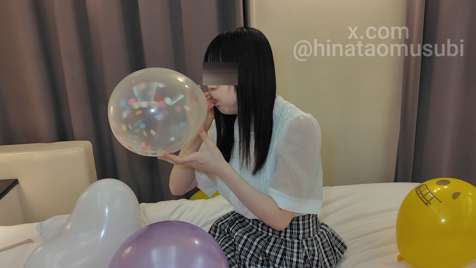 紙吹雪入りの透明な風船を膨らませる女。中のコンフェッティが見える。